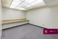 Small office room with long desk and overhead lighting